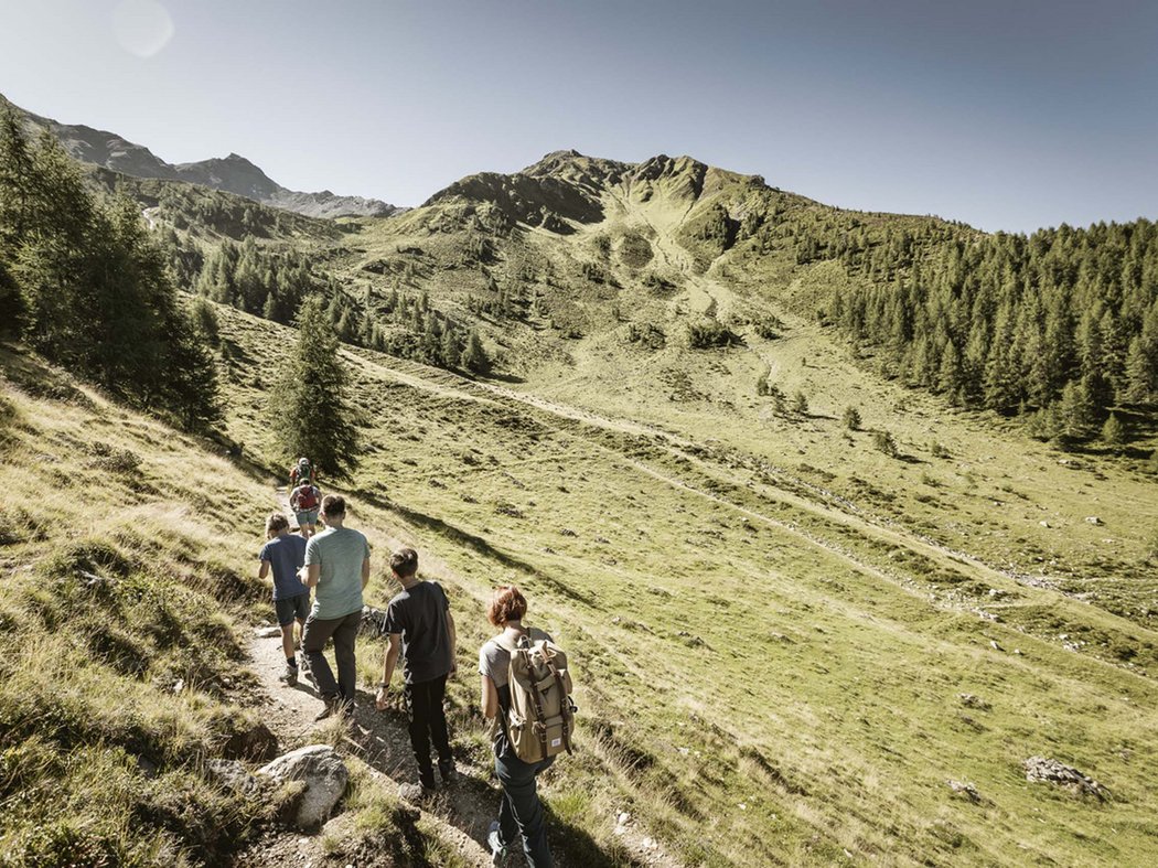 Exploring Kaunertal Group of hikers walking on a mountain trail in a sunny alpine landscape