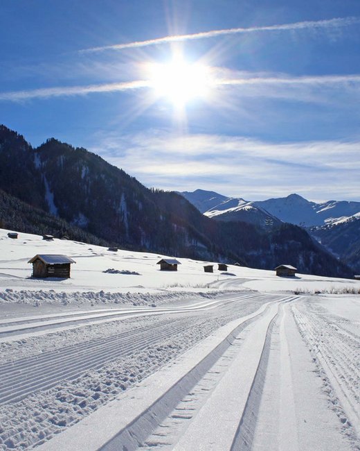 Ihr Urlaub im Sporthotel in Tirol Schneebedeckte Landschaft mit Skispuren und sonnigem Himmel über den Bergen