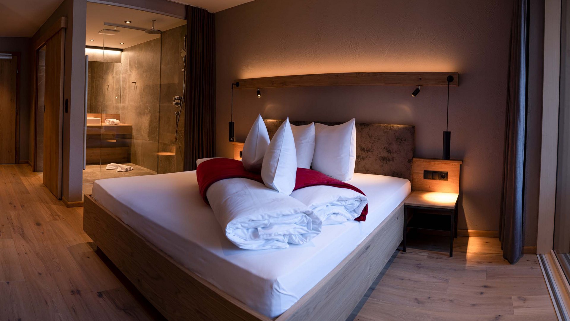 Ihr Wellnesshotel nahe der Schweizer Grenze Modernes Schlafzimmer mit Holzboden, Bett und offener Dusche im Hintergrund