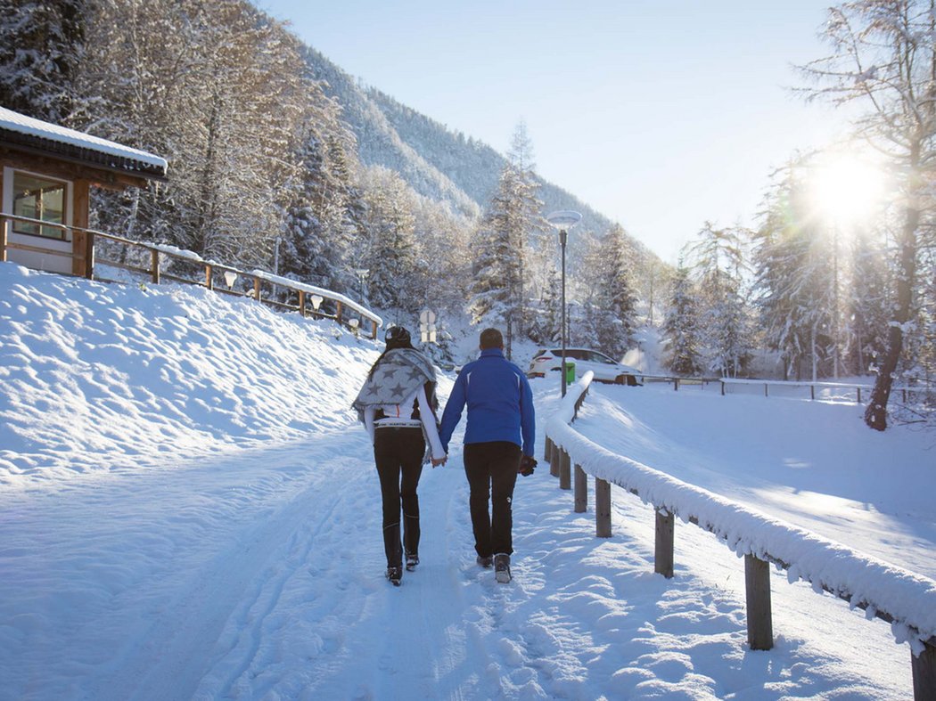 Die Faggenpromenade Paar hält Händchen beim Spazierengehen auf verschneitem Weg im Winter