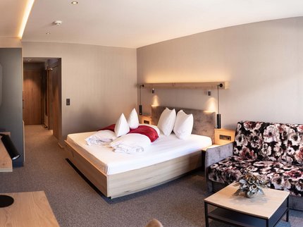 Urlaub im Kuschelhotel in Österreich Modernes Hotelzimmer mit Doppelbett und gemustertem Sofa