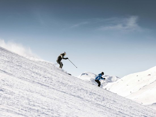 Echtes Kleinod aus dem Tiroler Oberland Zwei Skifahrer fahren einen verschneiten Hang bei klarem Himmel hinunter