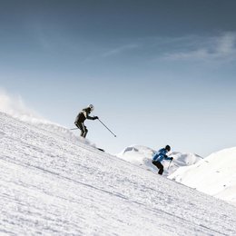 Ihr Wohlfühlort: das Hotel in Prutz im Tiroler Oberland ⛰️ Zwei Skifahrer fahren einen verschneiten Hang bei klarem Himmel hinunter