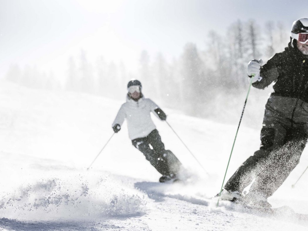 Your ski holiday preferences Two skiers skiing on a snowy slope during snowfall