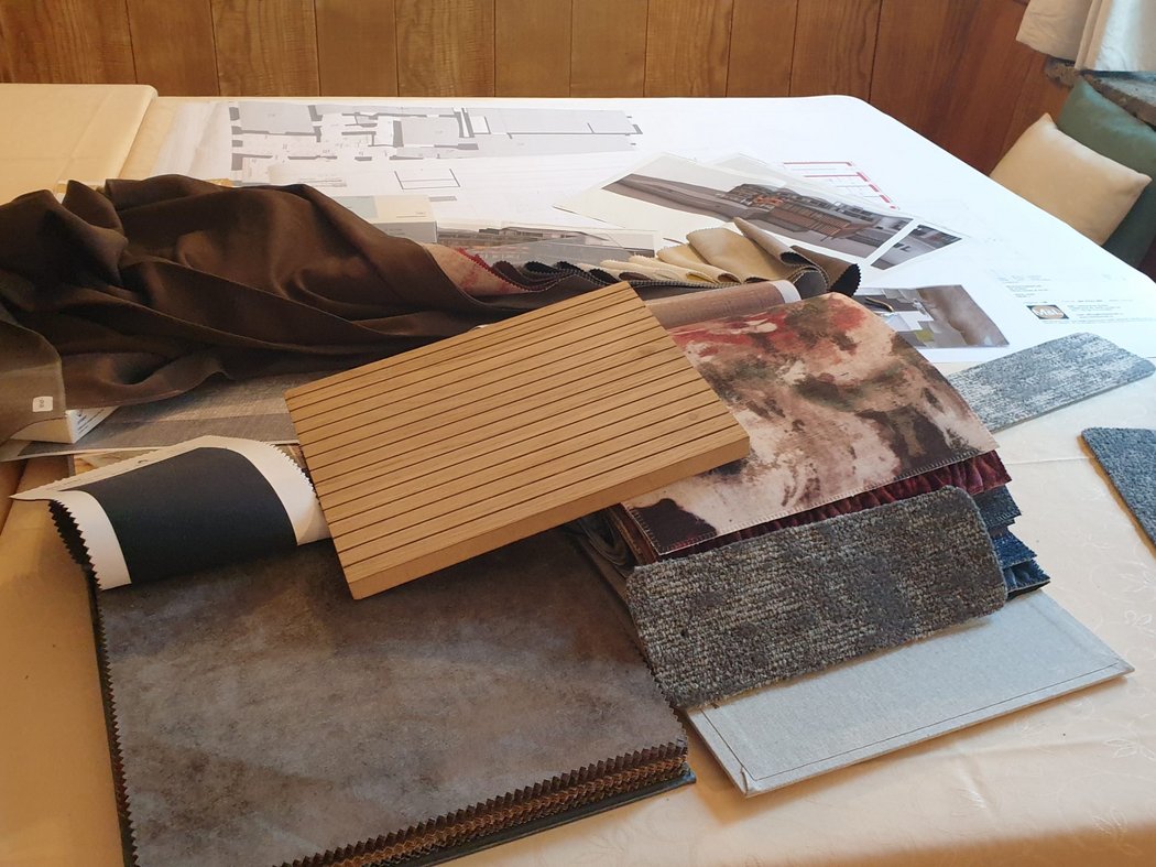 Nun geht es ans Einrichten Verschiedene Stoff- und Holzproben auf einem Tisch mit Bauplänen