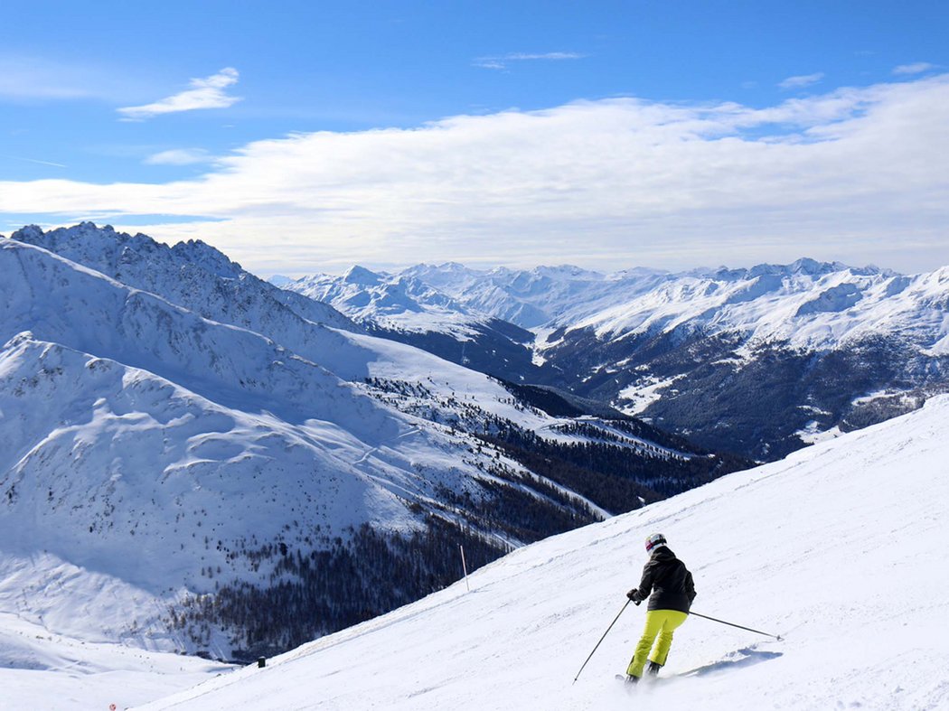 Magische Fünf Skifahrer fährt bergab auf schneebedecktem Hang mit Alpenpanorama