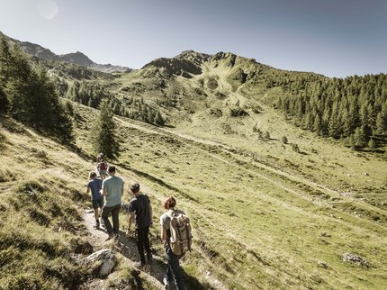 Looking for a hotel in Prutz? Group of hikers walking on a mountain trail in a sunny alpine landscape