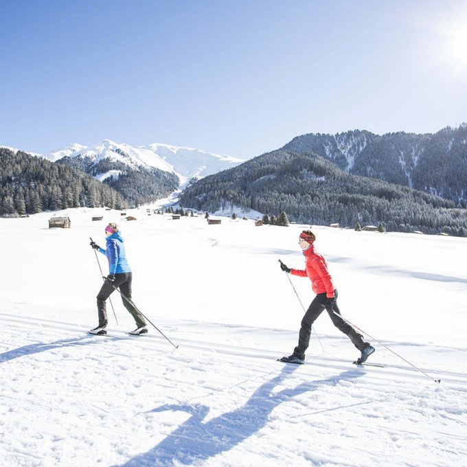 Ihr Urlaub im Sporthotel in Tirol Zwei Personen beim Langlaufen in verschneiter Berglandschaft bei Sonnenschein