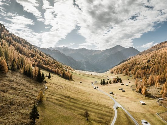 The blog of our accommodation in the Tyrolean Oberland Autumn mountain landscape with valley, pine trees, and scattered cabins