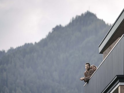 Urlaub im Kuschelhotel in Österreich Paar auf Balkon mit Bergblick im Hintergrund