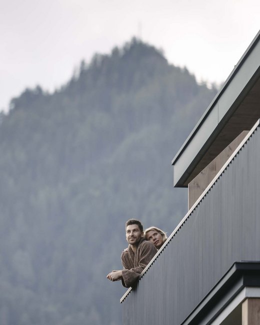 Feiern Sie Ihre Feste in Tirol Paar auf Balkon mit Bergblick im Hintergrund